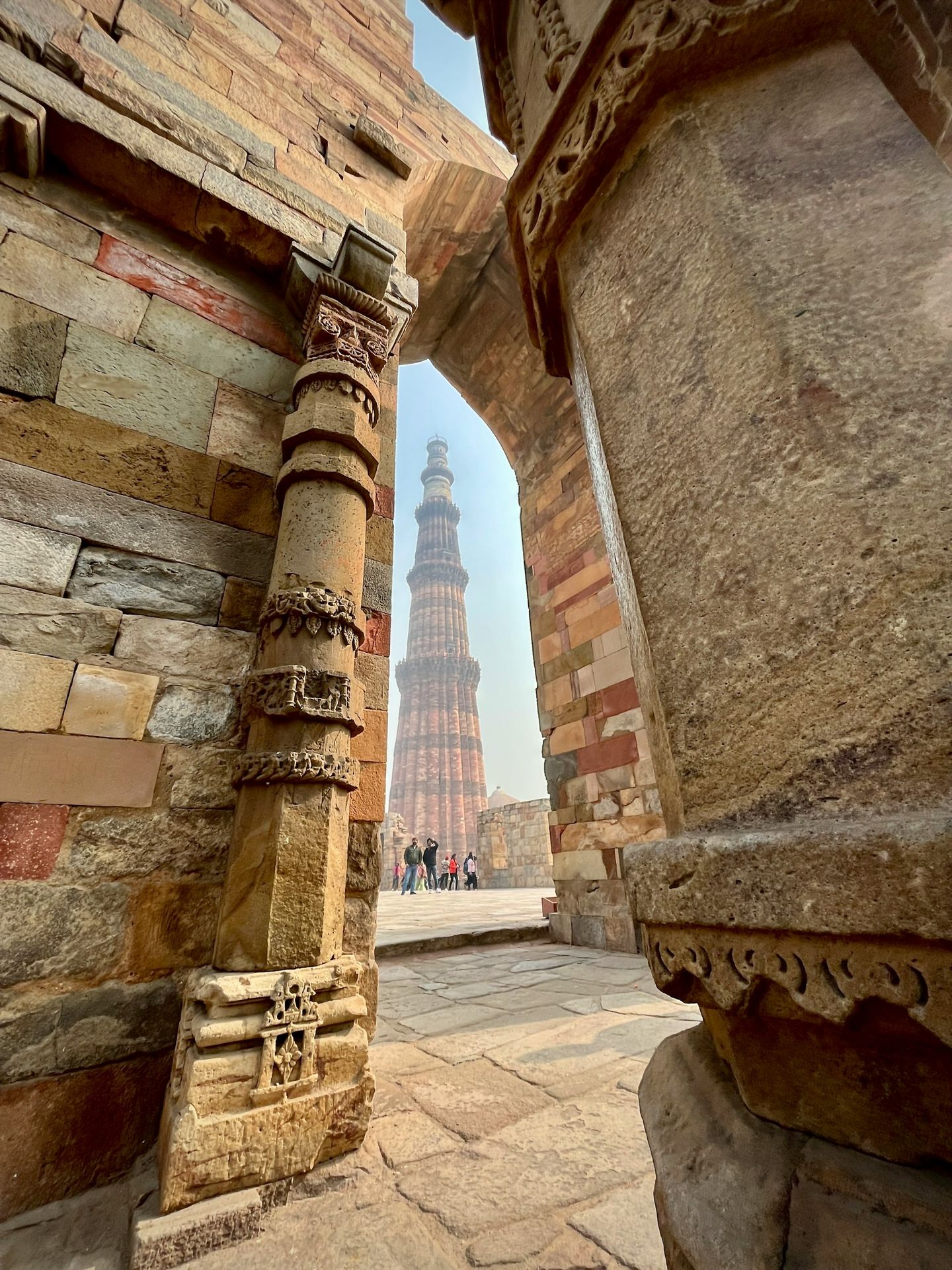a tall tower towering over a city next to a stone wall